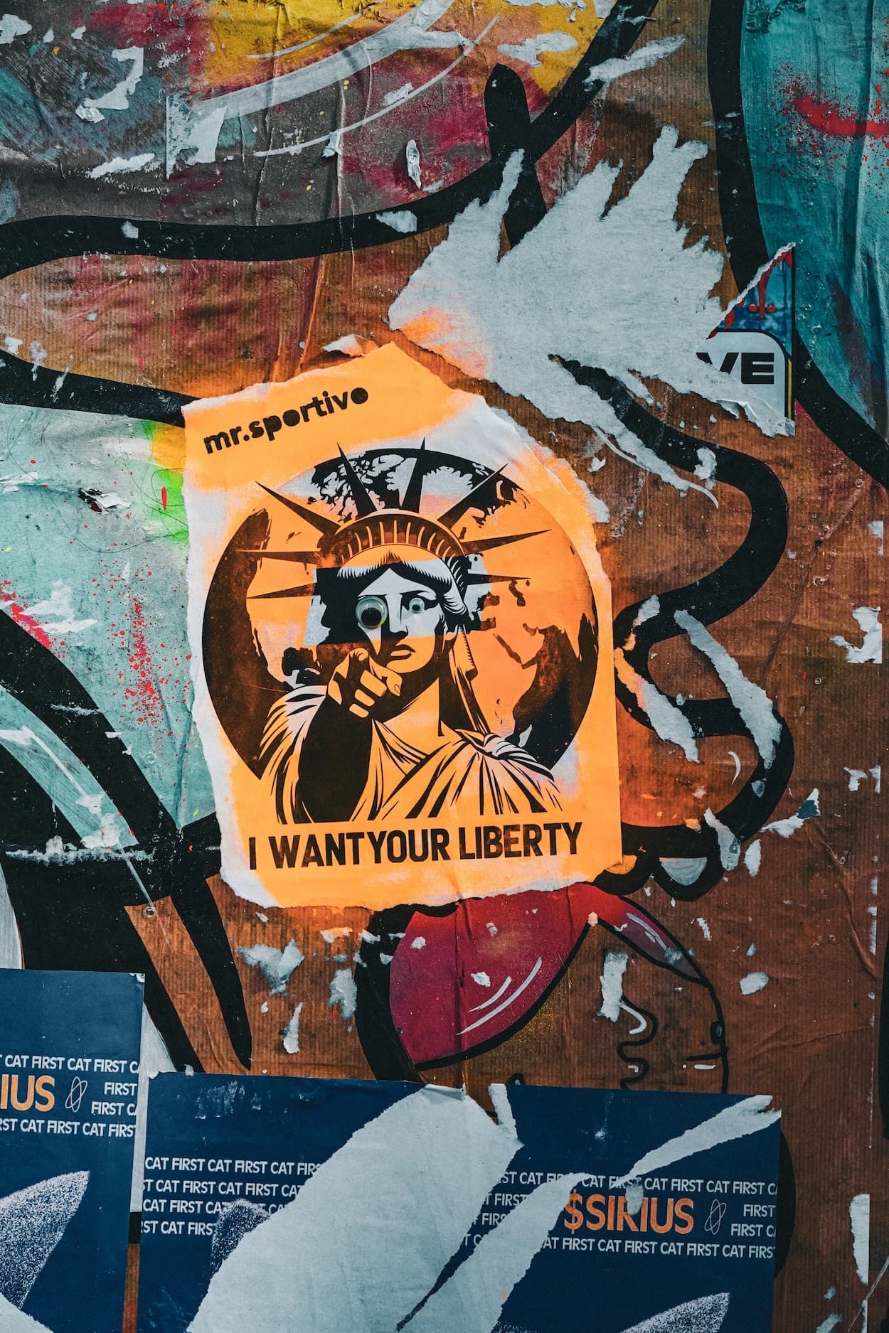 A torn orange flyposter of the Statue of Liberty pasted over layers of older prints and spray paint on a London wall
